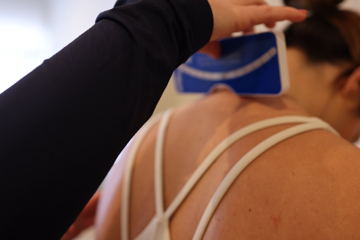 A practitioner measuring a patient's spine during an assessment